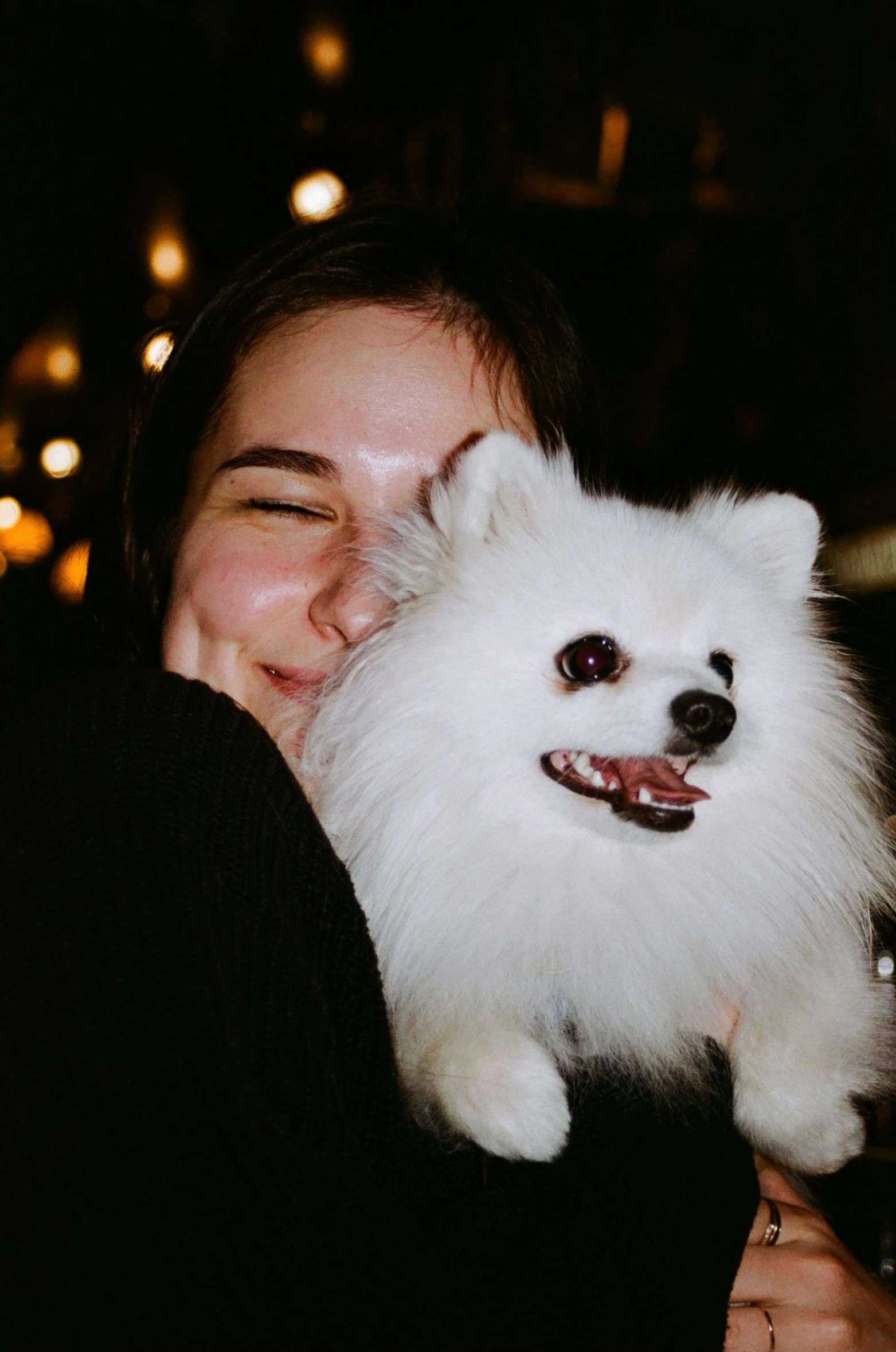 a person hugging a dog outside at night