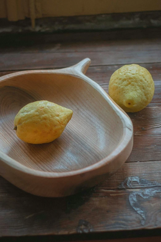 there are two pieces of lemon sitting in a wooden bowl