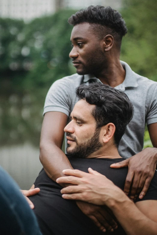 a couple of men sitting next to each other on top of a hill