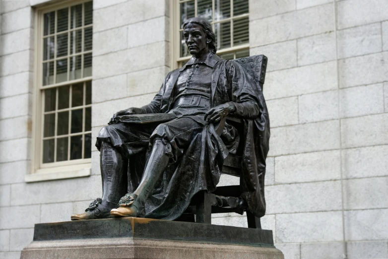 the statue of a man sitting in a chair near an older man