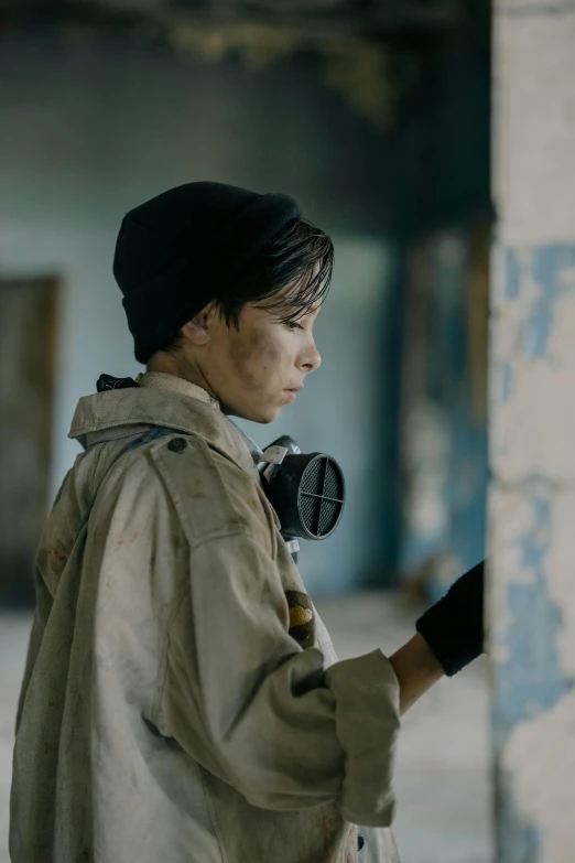 a young man with a gas mask on standing by a pillar