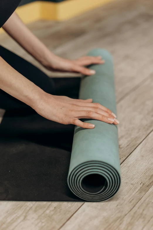 a woman sitting on a yoga mat reaching down