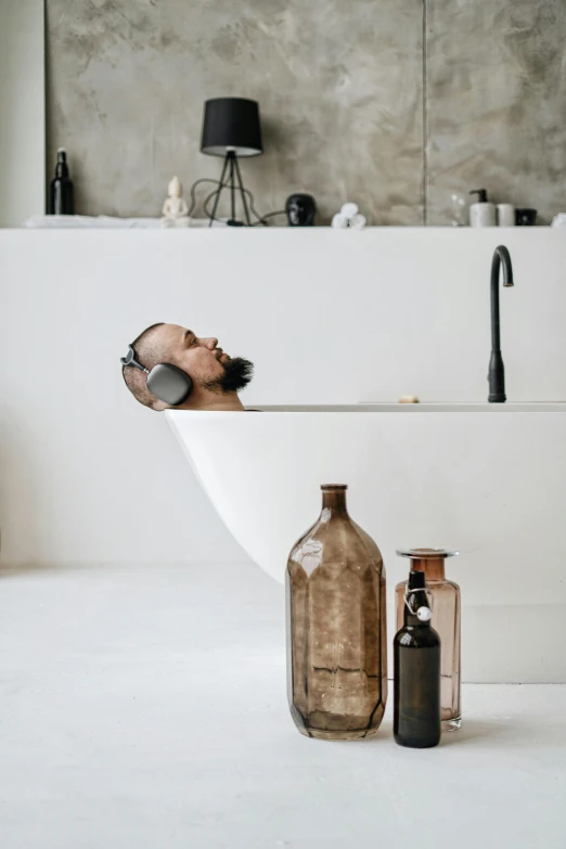 a po showing the inside of a bath room, with a glass bottle and metal spoon, next to an antique medicine jar and a soap container