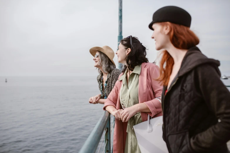 three woman look off into the distance from a ship railing