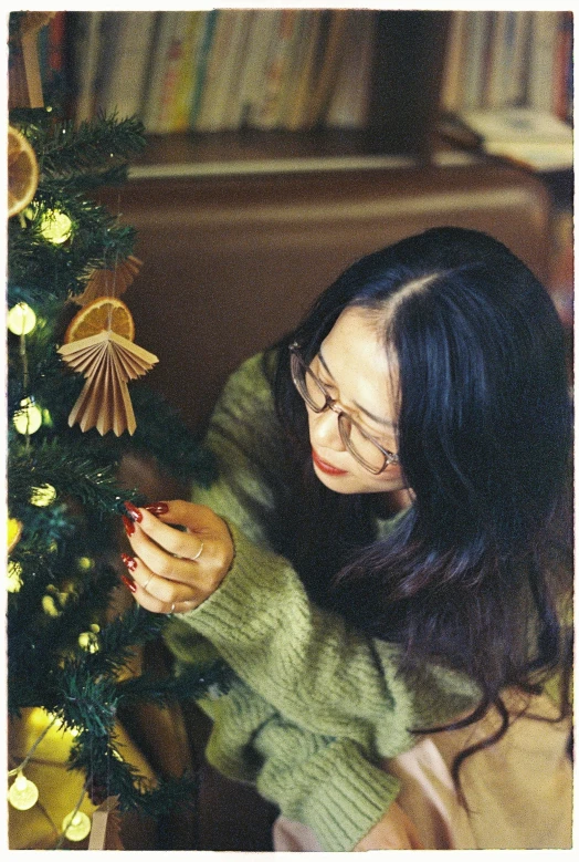 a young woman decorating a christmas tree with a mobile phone