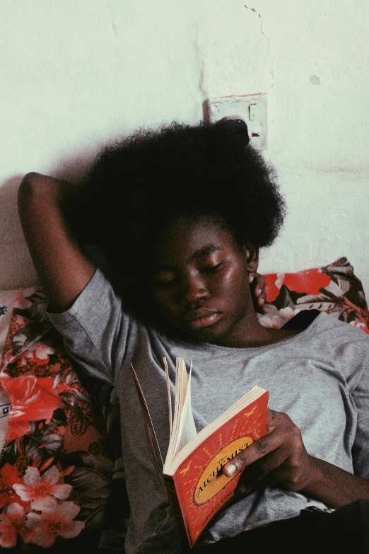 black woman reading a book while laying on couch