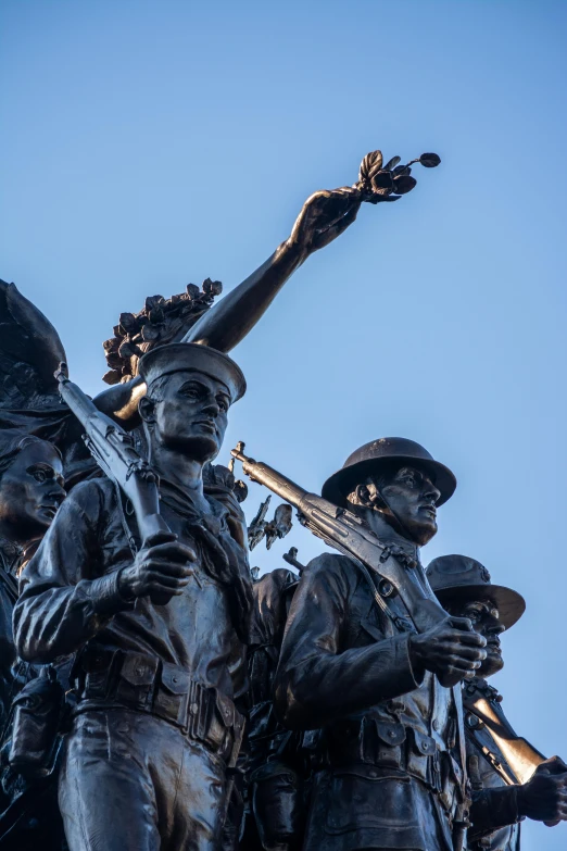 a statue in front of a blue sky with arms spread