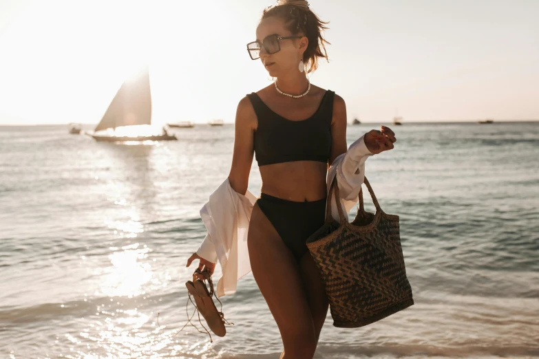 a woman with a hand bag walks on the beach