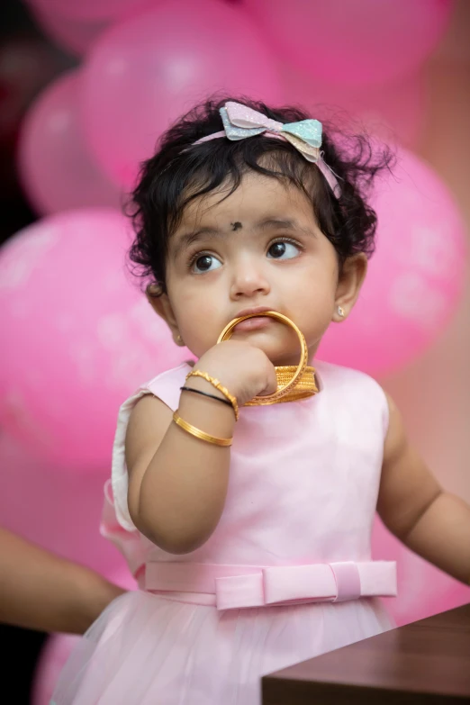 a little girl posing in front of pink balloons