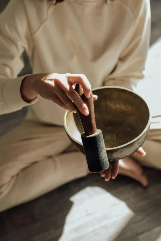 a woman holding a bowl of food sitting on the floor