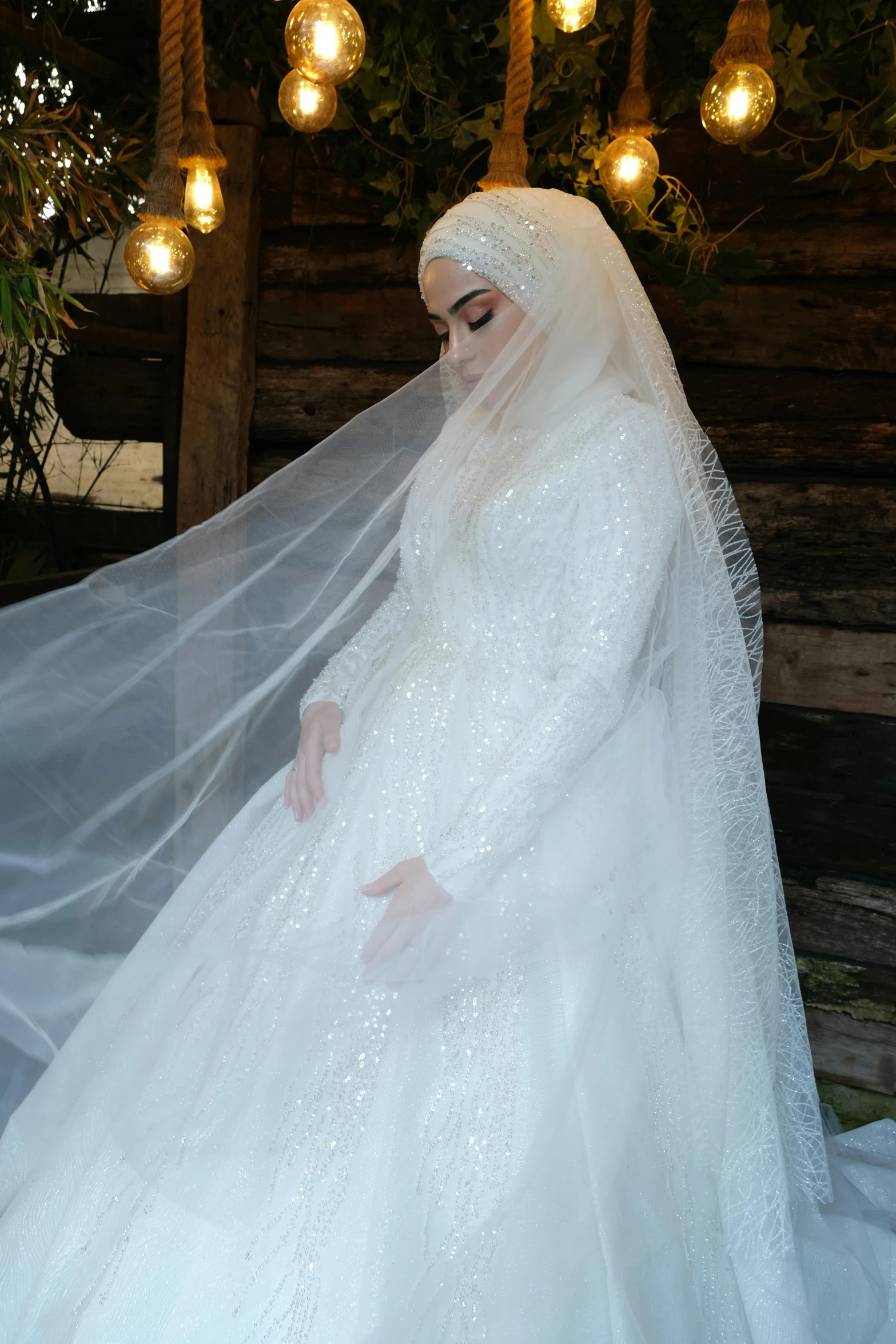 a woman in white wearing a veil and sitting outside