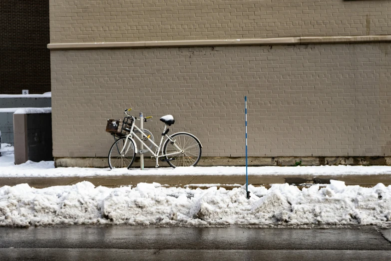 the bike is parked by the curb with snow on it