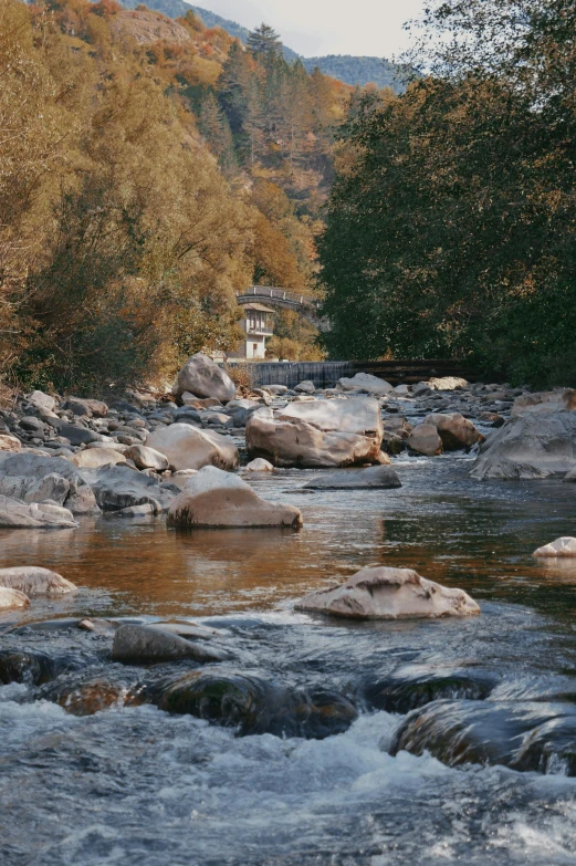 the view from the river bed of mountains and trees, with small buildings