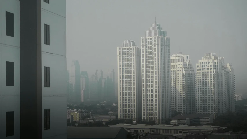several tall buildings are seen in a hazy sky
