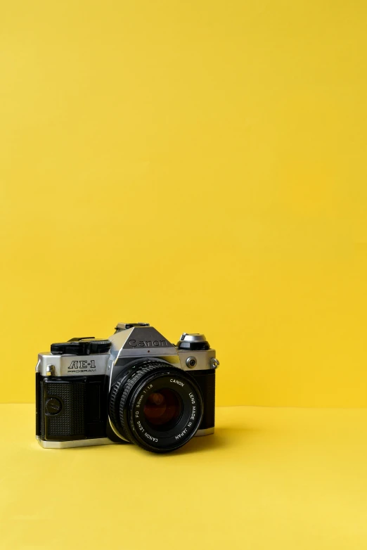 an old camera is placed against a yellow background