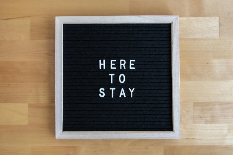 a letter board with the words here to stay spelled on it