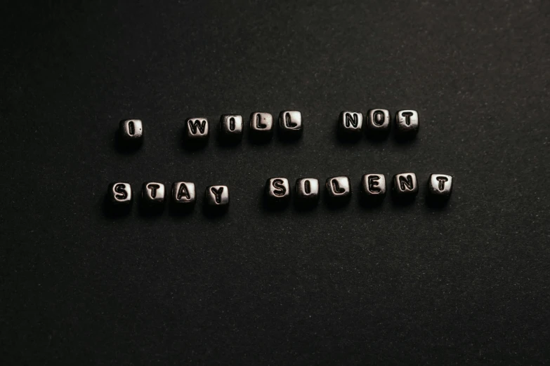 the letters of metal beads are on a black surface