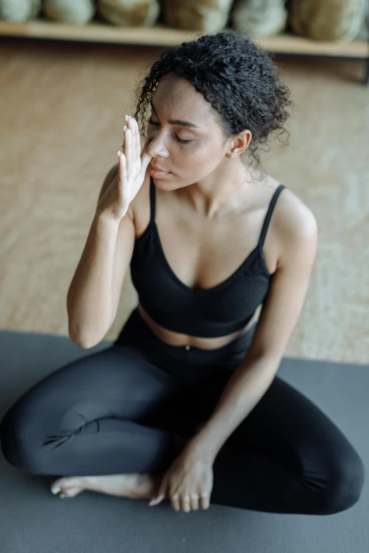 woman sitting on a mat looking at her face