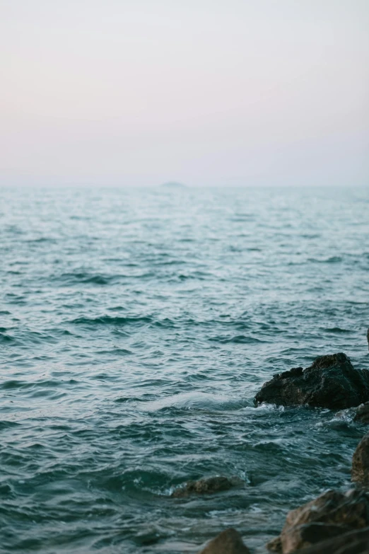 an open body of water with rocks on one side and waves on the other