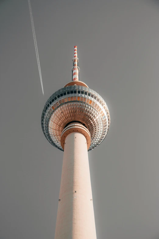 there is a airplane flying in the sky next to a tall structure