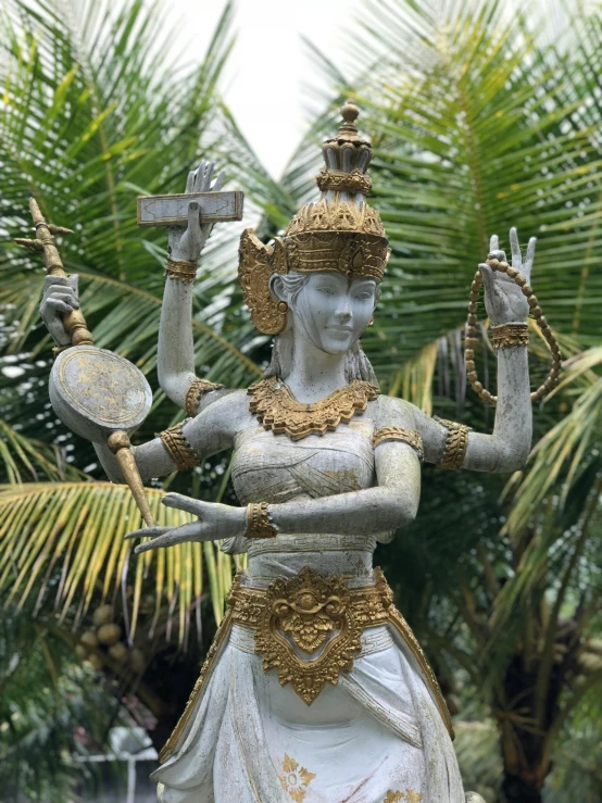 a white statue sitting next to green trees