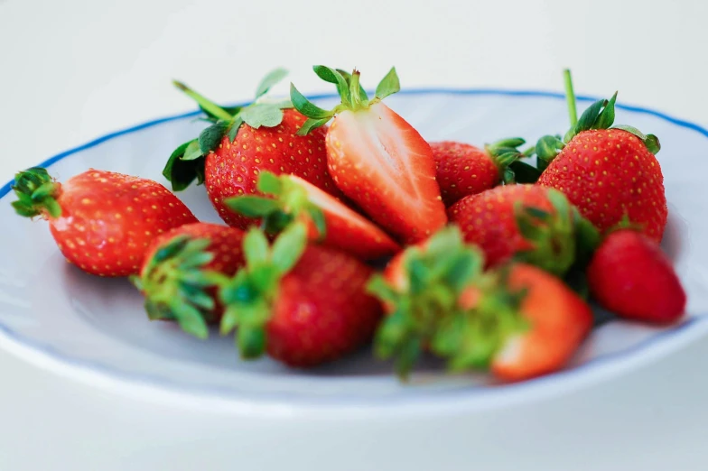 a plate filled with fresh strawberries sitting on a white table