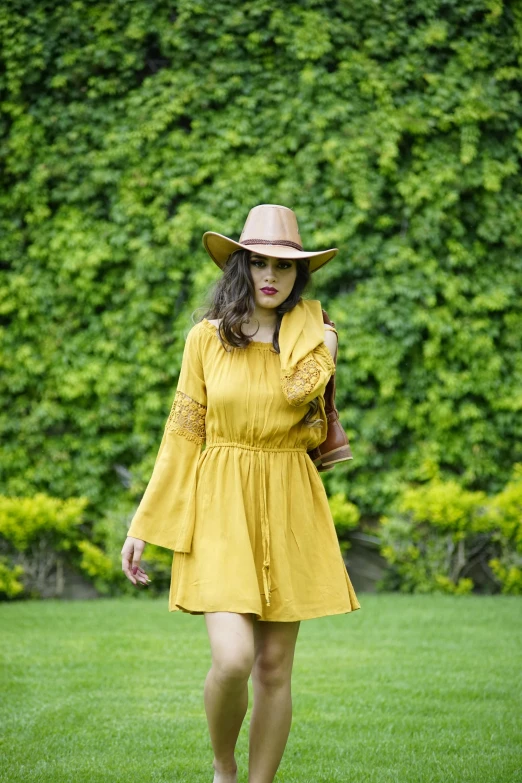 a woman in a yellow dress and hat walking