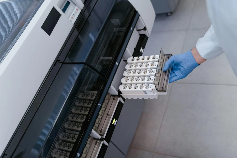 a person in blue gloves and gloves puts the top tray of food in a microwave