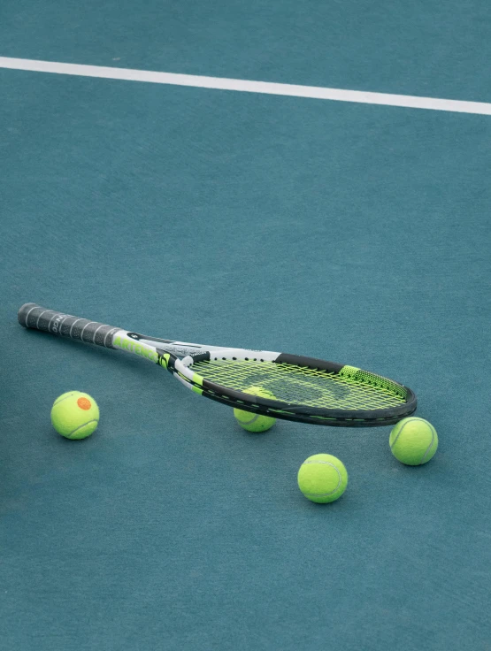 a person reaching for three tennis balls with their racket and balls