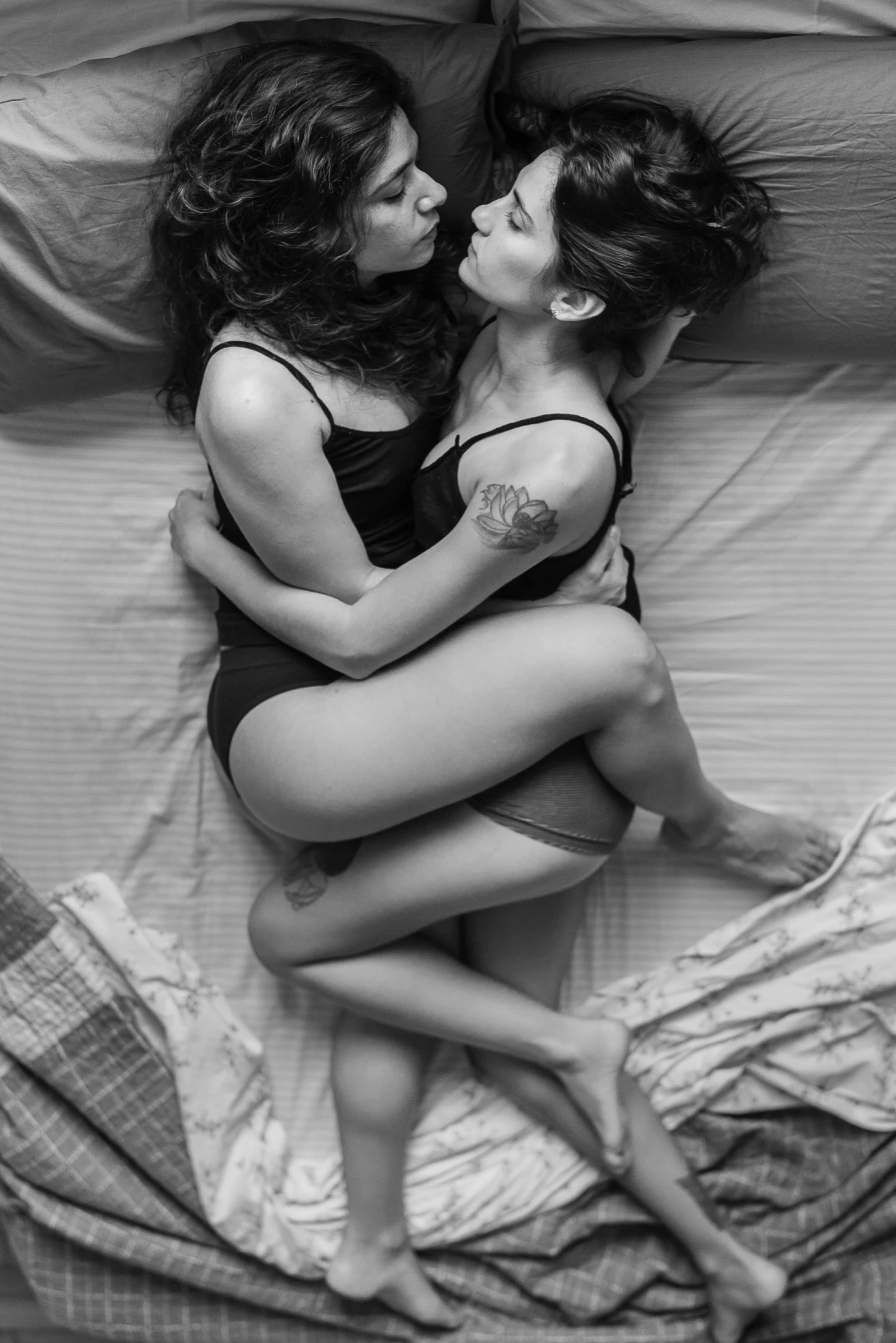 two girls are kissing each other while laying in bed