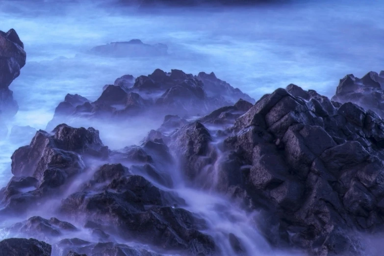 the waves crash around rocks on the beach