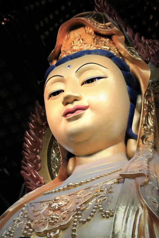 a statue of buddha with open eyes and gold accents