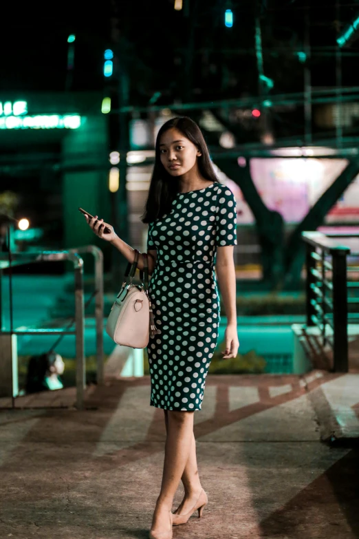 a beautiful young lady holding a bag and looking at her phone