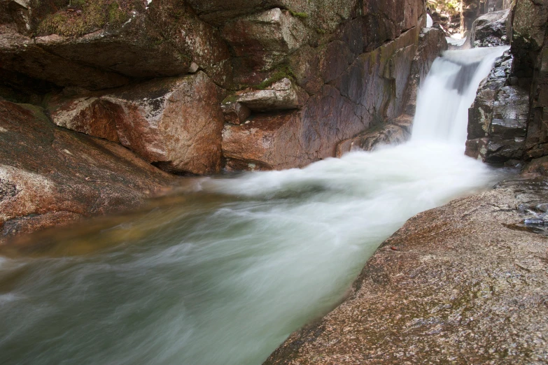 a man sitting on top of a large rock near a waterfall