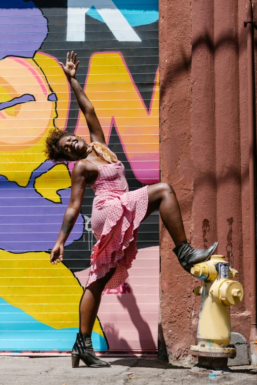 a woman is posed in front of a wall with graffiti