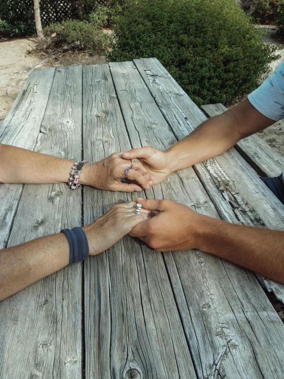 two people are holding hands over a picnic table