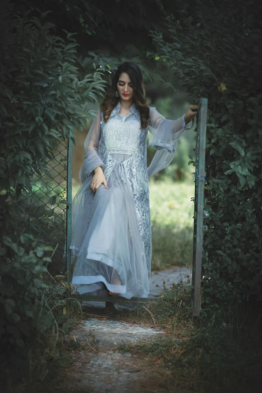 a beautiful young woman dressed in a long silver dress