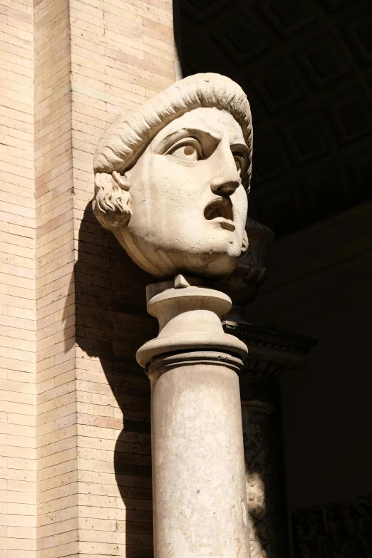 a statue head is against a pillar on the side of a building