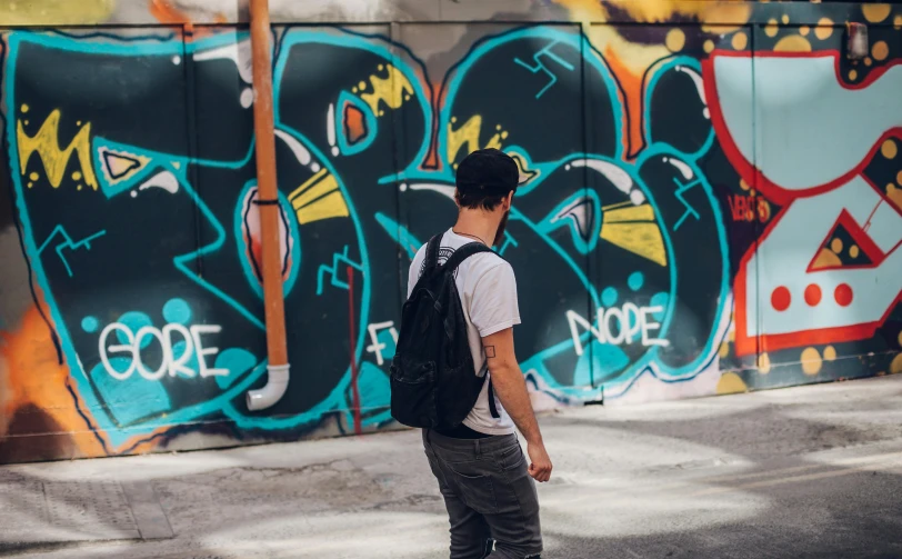 a boy riding a skateboard down a street with graffiti on the walls behind him