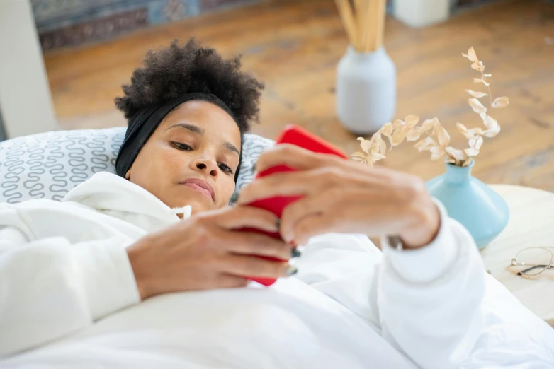 woman lying in bed looking at a red object