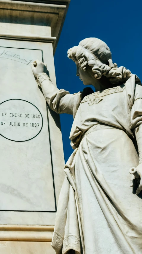 an old statue standing next to a plaque on top of a building