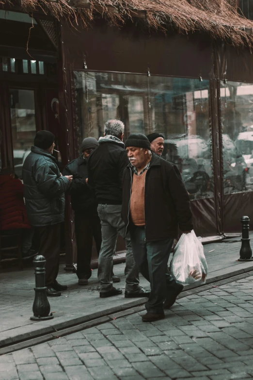 an old man walking down a city street with his groceries