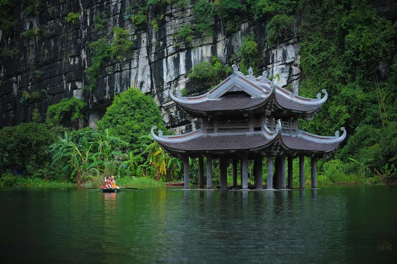 a pagoda near the water in front of some tall rocks