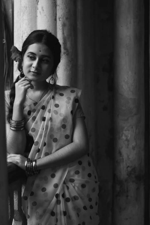 a woman in sari stands next to pillars