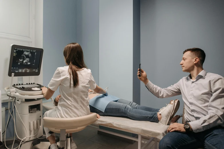 a young man taking a picture of a woman laying on a bed