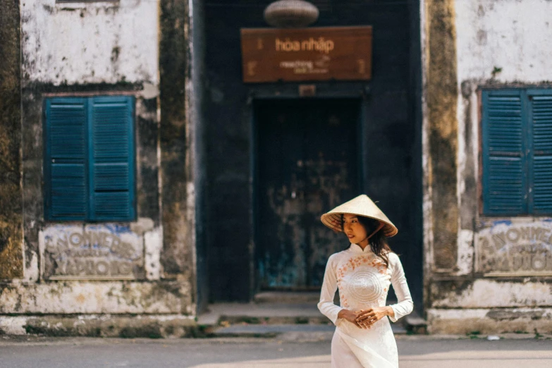 a woman standing outside of a building with a big hat