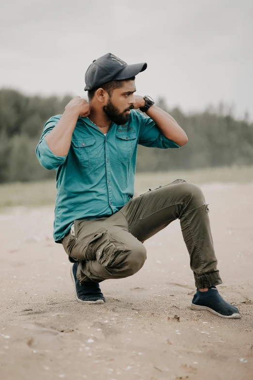 a man crouches in the sand and takes a picture