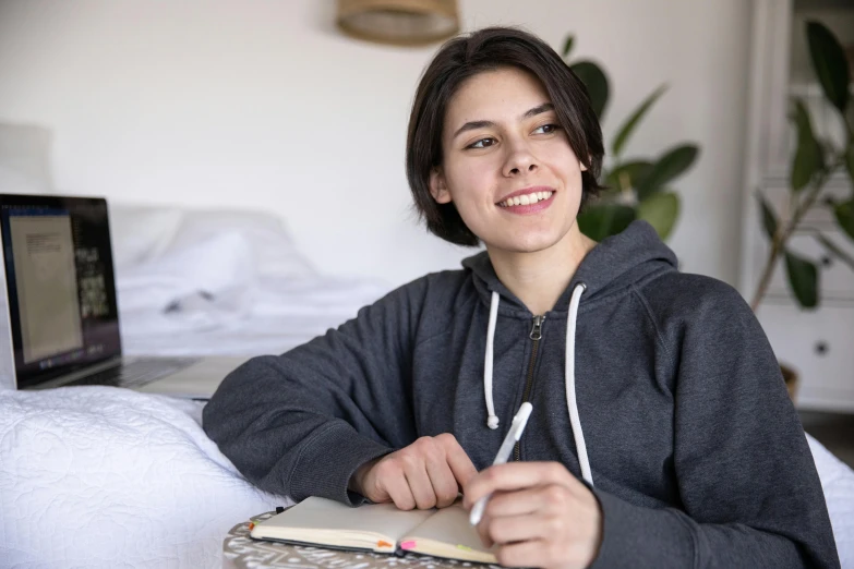 a woman sitting on a couch holding a notebook and smiling