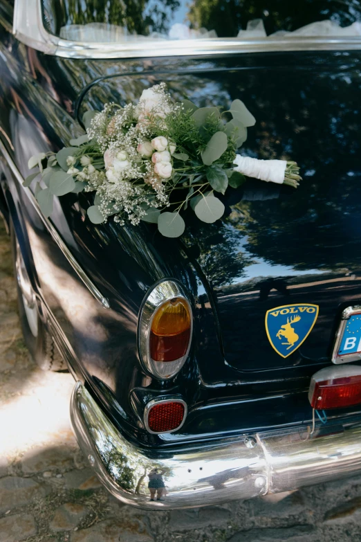 there is an old black car with a flower arrangement on the hood