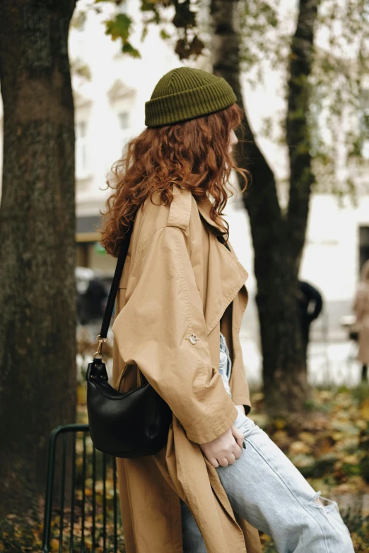 a woman standing on a street corner holding onto her purse